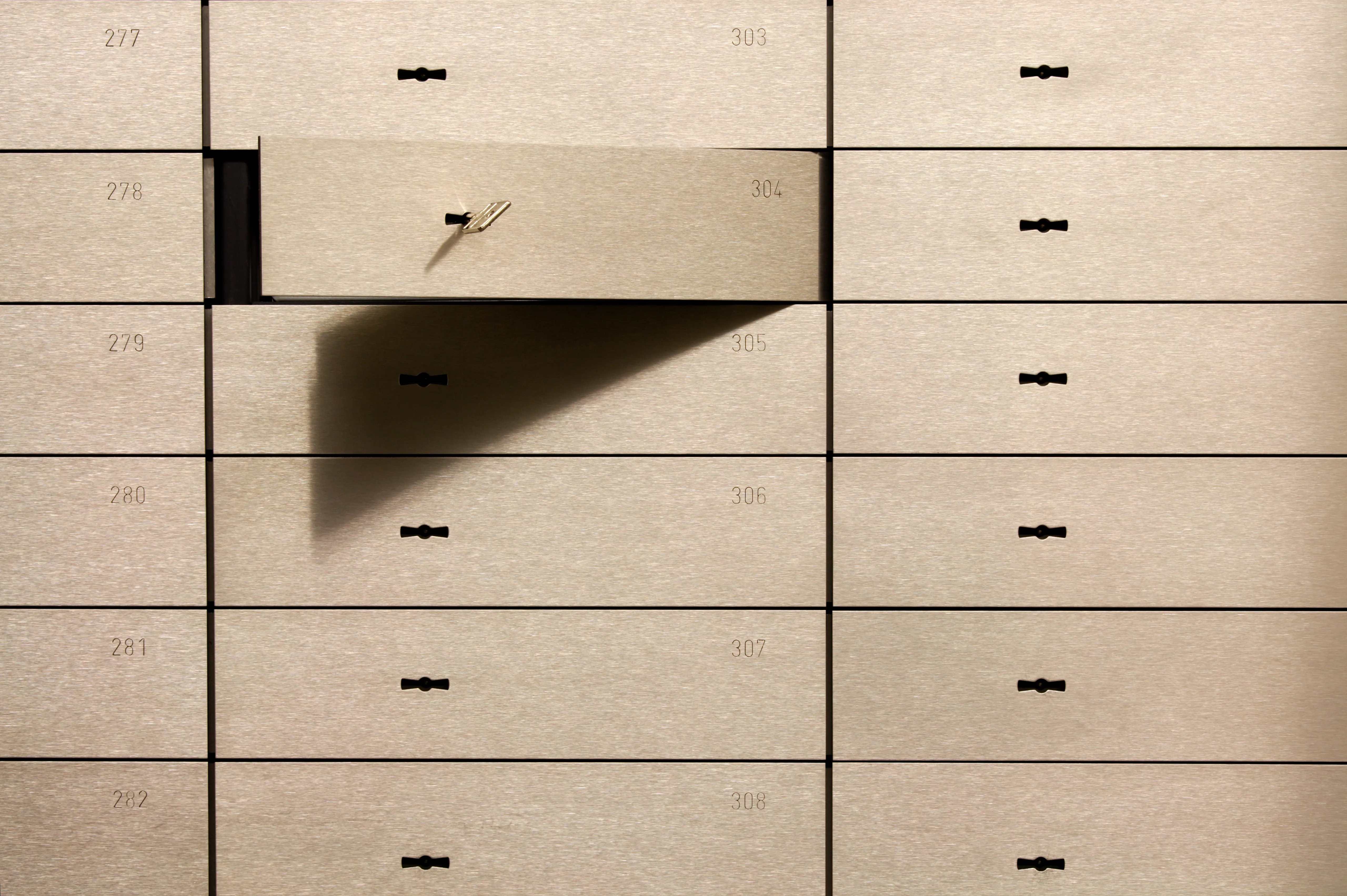 Geöffnetes Bankschließfach mit Schlüssel in einer Reihe nummerierter Schließfächer