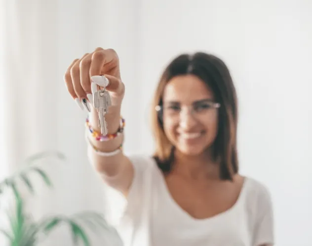 Hand mit Hausschlüssel und Schlüsselanhänger in Hausform in München